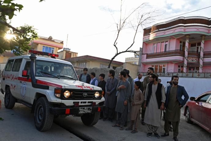 Varios viandantes se paran junto a una ambulancia cerca del lugar de una explosión en Kabul.