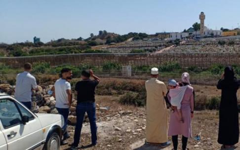 La familia del joven fallecido en Melilla ve el funeral desde la valla. La familia del joven fallecido en Melilla ve el funeral desde la valla.