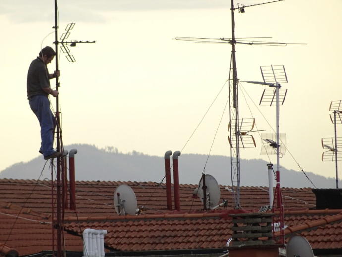 Imagen de un técnico instalando una antena de tv.