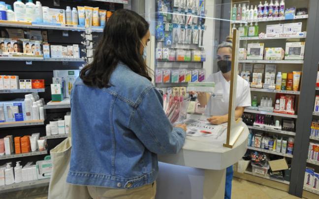 Una mujer compra test de antígenos en una farmacia.