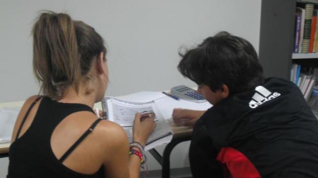 Una voluntaria ayuda a un joven con desfase escolar.