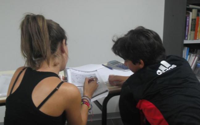 Una voluntaria ayuda a un joven con desfase escolar.