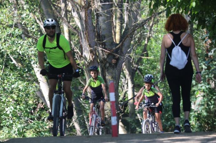 Gente en bicicleta y paseando por el paseo del Arga