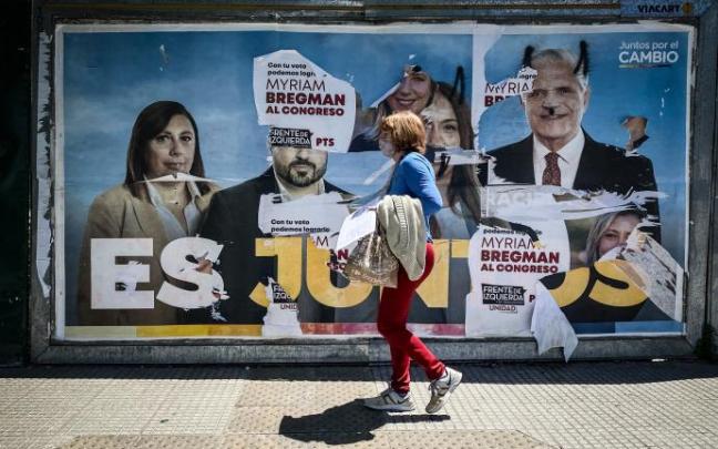 Una mujer ante un cartel con publicidad electoral en Buenos Aires