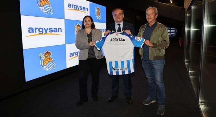 Los representantes de Argysan posan con Jokin Aperribay y la camiseta txuri-urdin