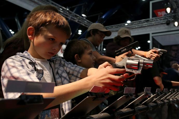 Dos niños probando armas en una reunión de la Asociación Nacional del Rifle.