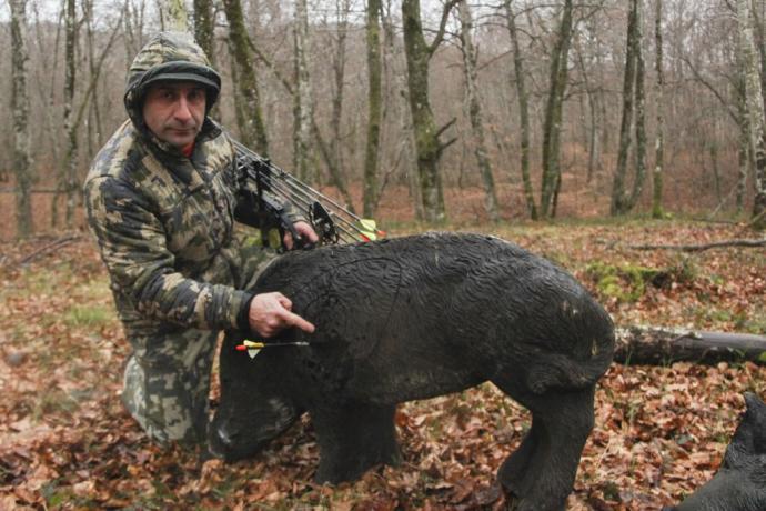 Un arquero posa junto a una figura de un jabalí.