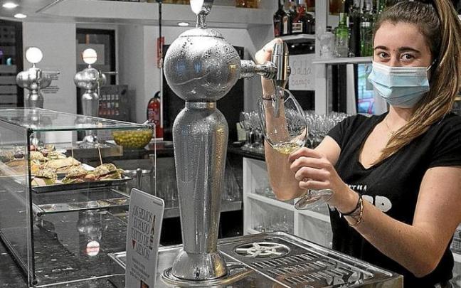 Una camarera sirve una caña con mascarilla. Foto: Iker Azurmendi