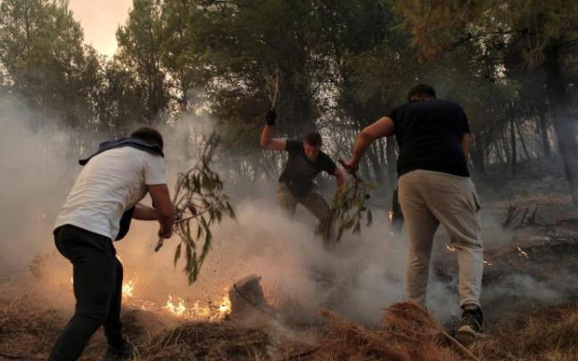 Varios jóvenes usan ramas de árboles mientras luchan contra un incendio en el área de Tatoi, cerca de Atenas. Varios jóvenes usan ramas de árboles mientras luchan contra un incendio en el área de Tatoi, cerca de Atenas.