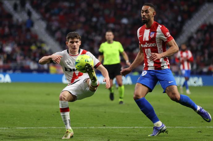 El delantero brasileño del Atlético de Madrid, Matheus Cunha (d), disputa un balón con Fran García (i), defensa del Rayo Vallecano,