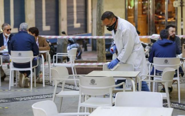 Un trabajador de hostelería limpiando una terraza Un trabajador de hostelería limpiando una terraza