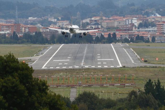 Un avión a punto de aterrizar con viviendas de Derio al fondo