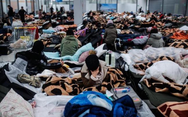 Varias personas descansan en un centro comercial destinado a la acogida temporal de los refugiados, en Polonia.