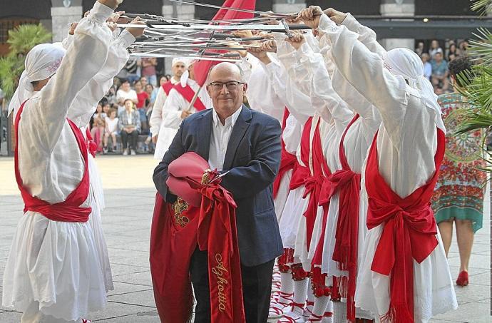 El alcalde, Javier Zubizarreta, pasa con la bandera colorada bajo un arco realizado por los ezpata-dantzaris