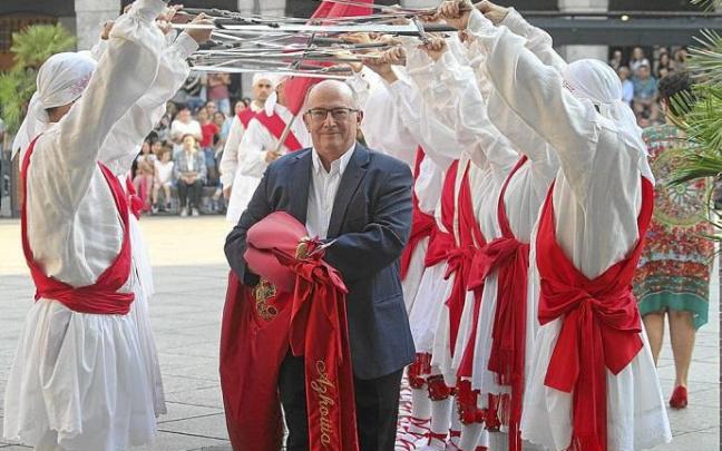 El alcalde, Javier Zubizarreta, pasa con la bandera colorada bajo un arco realizado por los ezpata-dantzaris