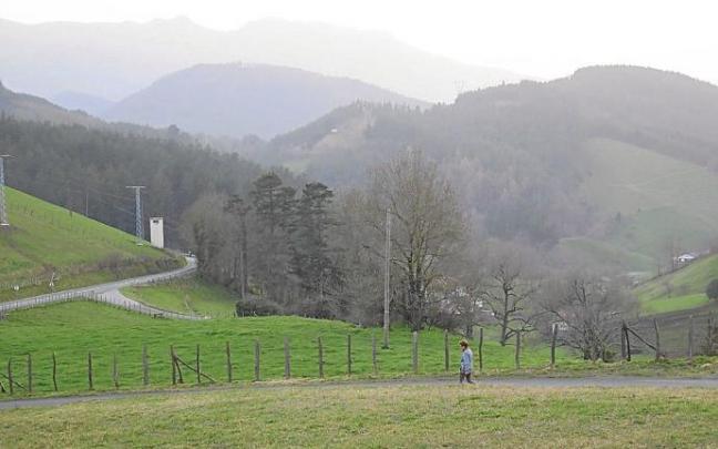 Una mujer pasea por Aztiria, con Aizkorri al fondo. Una mujer pasea por Aztiria, con Aizkorri al fondo.