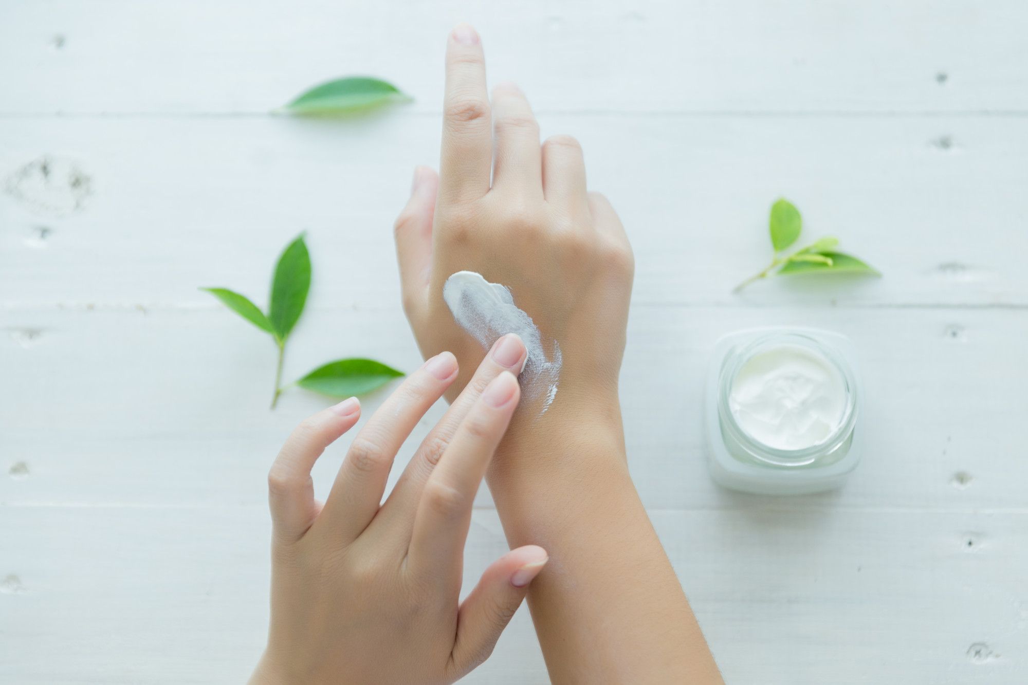 Una mujer se da crema hidratante en la mano.