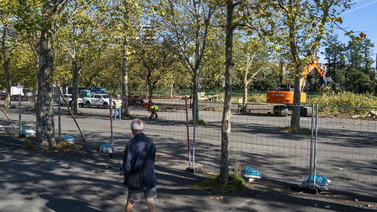 Un hombre camina junto a la zona vallada en la que se construirá el campo de hockey.