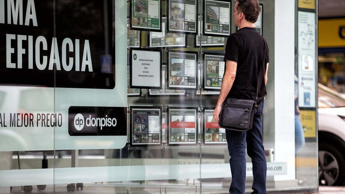 Imagen de archivo de un hombre observando el escaparate de una inmobiliaria con anuncios de pisos en venta y alquiler.