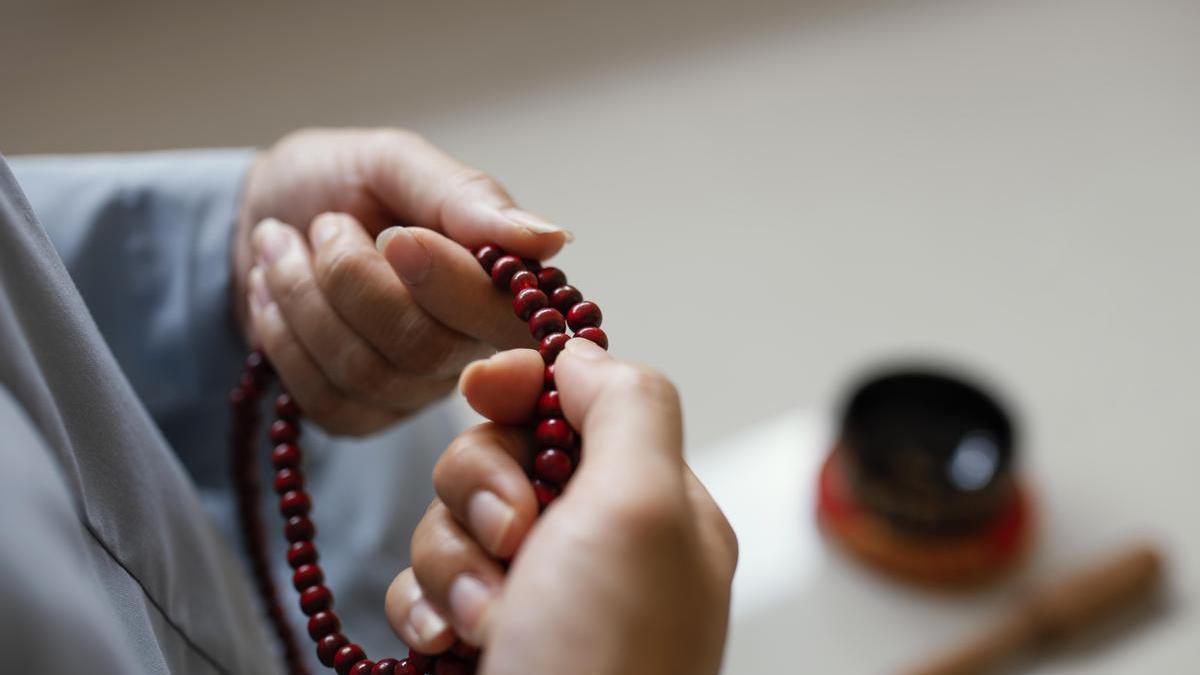 Una mujer sostiene un rosario entre sus manos.