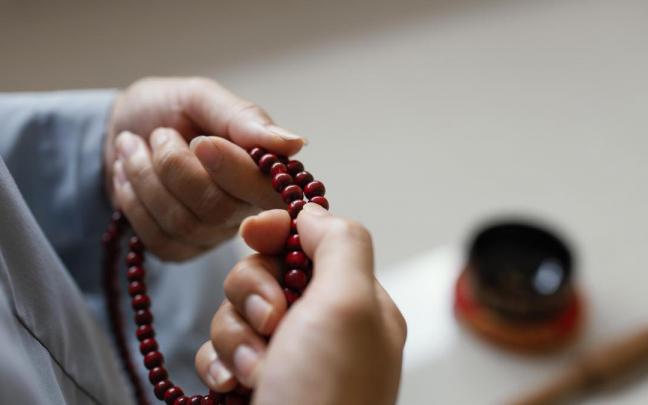 Una mujer sostiene un rosario entre sus manos. Una mujer sostiene un rosario entre sus manos.