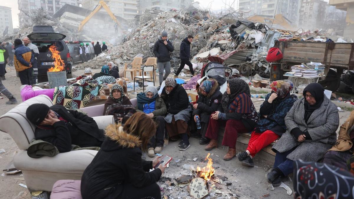 Personas sin casa sentadas en la calle en torno a una hoguera tras el terremoto de Turquía.
