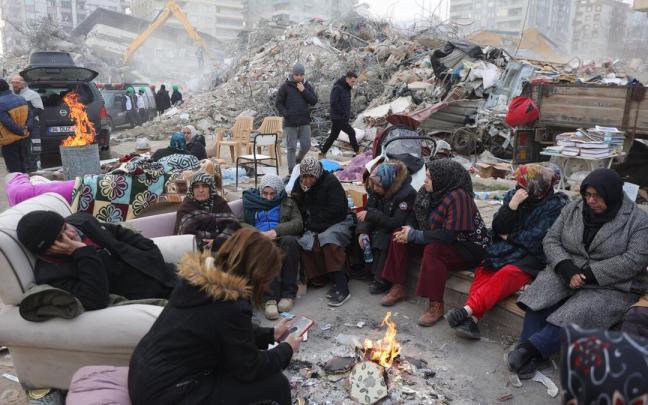 Personas sin casa sentadas en la calle en torno a una hoguera tras el terremoto de Turquía.