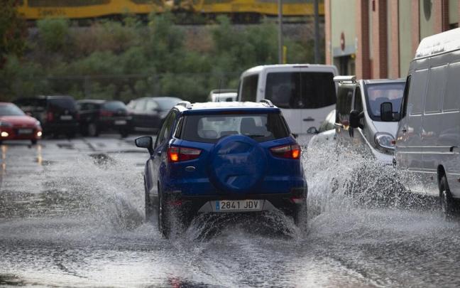 Un coche pasa sobre una gran balsa de agua Un coche pasa sobre una gran balsa de agua