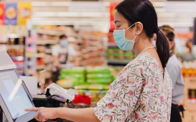 Una mujer pasa la compra por un cajero de autopago.