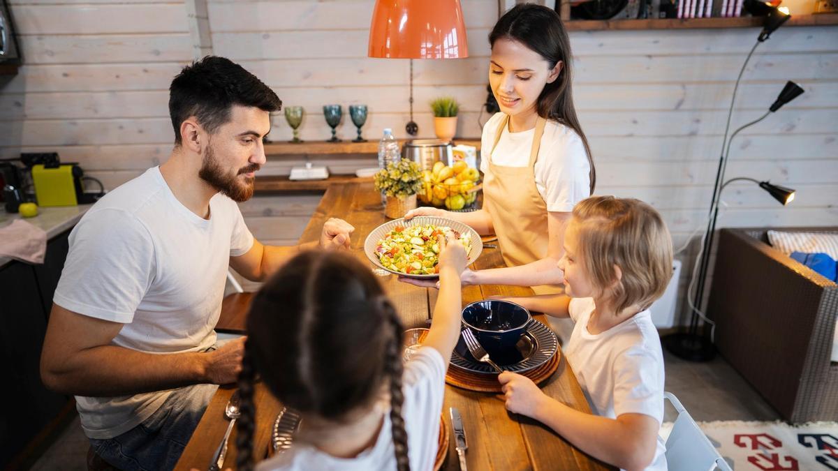 Una familia sentada a la mesa para cenar.