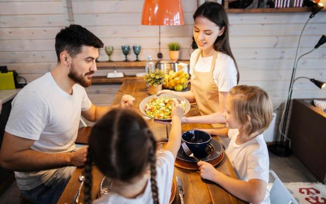 Una familia sentada a la mesa para cenar.