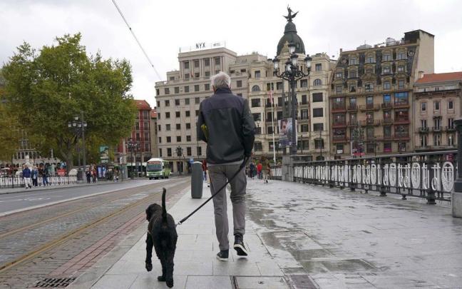 Un hombre pasea con su perro por el puente de El Arenal de Bilbao.