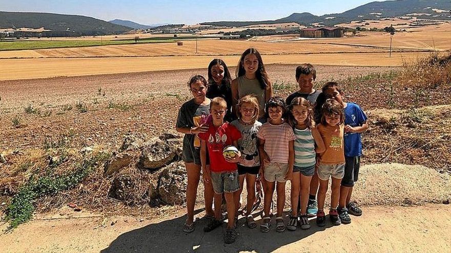 Niños y niñas en Oco, y al fondo los terrenos donde se ubicaría el parque solar.