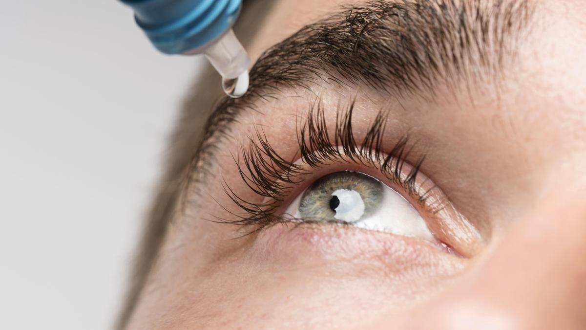Un joven se hidrata los ojos con gotas.