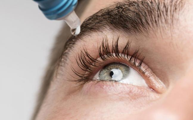 Un joven se hidrata los ojos con gotas.