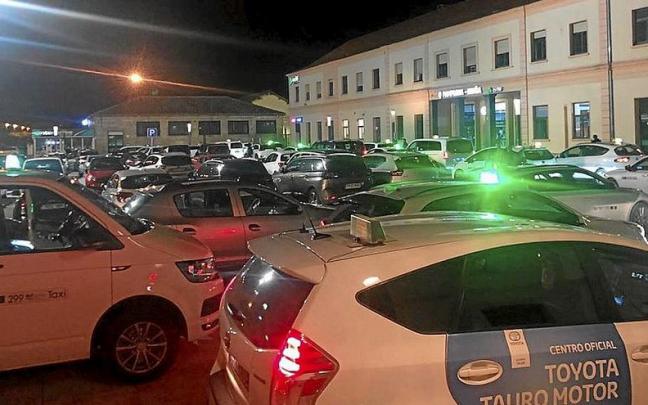 Taxistas agolpados este viernes frente a la estaci&oacute;n del tren esperando clientes.
