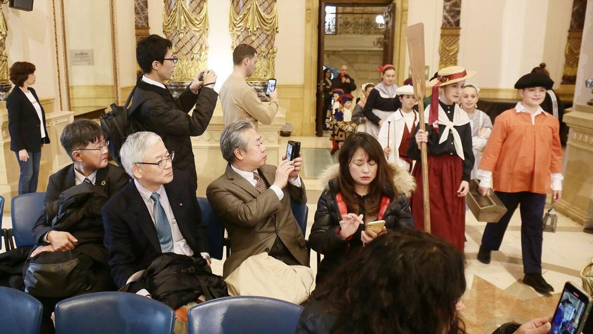 Unos visitantes japoneses asisten a la entrada de los cargos de la Tamborrada Infantil en el Ayuntamiento.