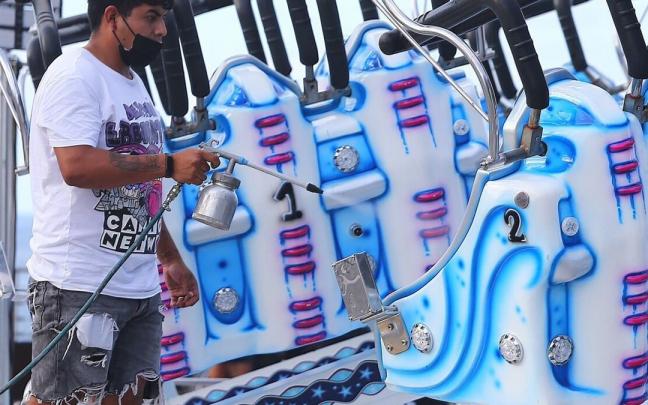 Un feriante pone a punto una de las atracciones el pasado año.