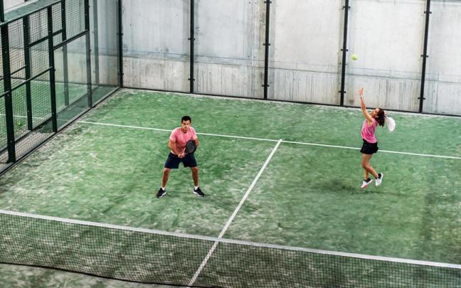 Una pareja practica pádel en una pista cubierta. Una pareja practica pádel en una pista cubierta.