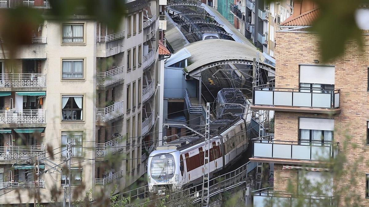 El tren en dirección Irun tras salir de la estación de Pasai Antxo, encajonada entre multitud de casas.