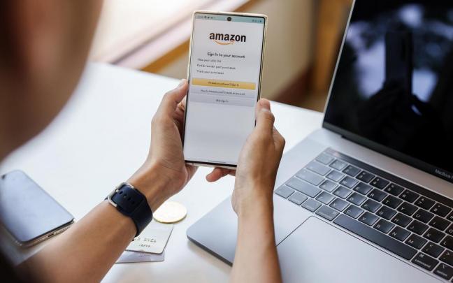 Una persona compra en Amazon con su teléfono y su ordenador.