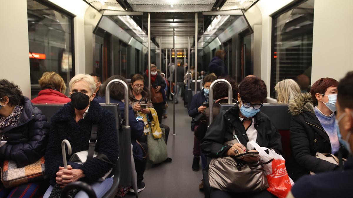 Un pasajero con mascarilla consulta su móvil en el interior de un vagón del metro.