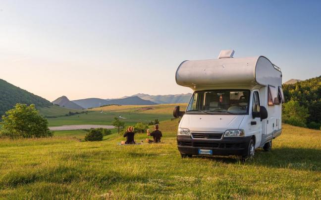 Dos personas disfrutan de un paisaje junto a su autocaravana. Dos personas disfrutan de un paisaje junto a su autocaravana.
