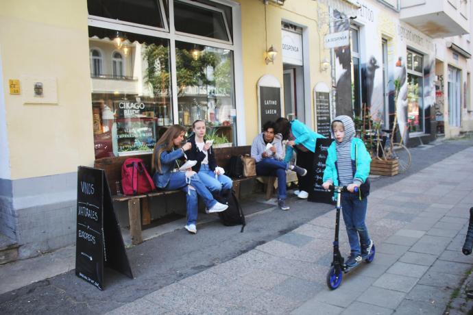 Un grupo de personas comen en los bancos de un bar-tienda en Berlín.