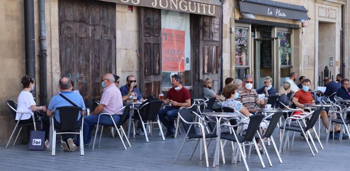 Personas sentadas en la terraza de un bar con mascarilla para evitar contagios de coronavirus.