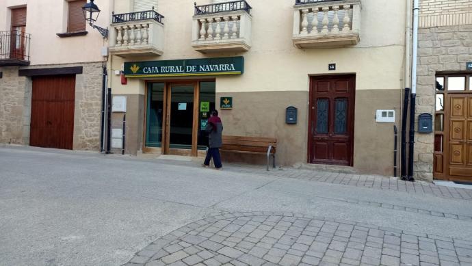 Una vecina pasea por delante de la sucursal de Bargota donde hay un nuevo cajero y donde está también el desfibrilador municipal.