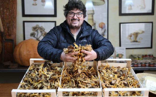 Tatxo Martínez posa junto a cajas repletas de setas en su tienda de la Rochapea.