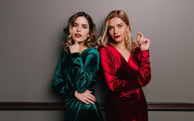 Dos mujeres lucen vestidos de terciopelo. Dos mujeres lucen vestidos de terciopelo.