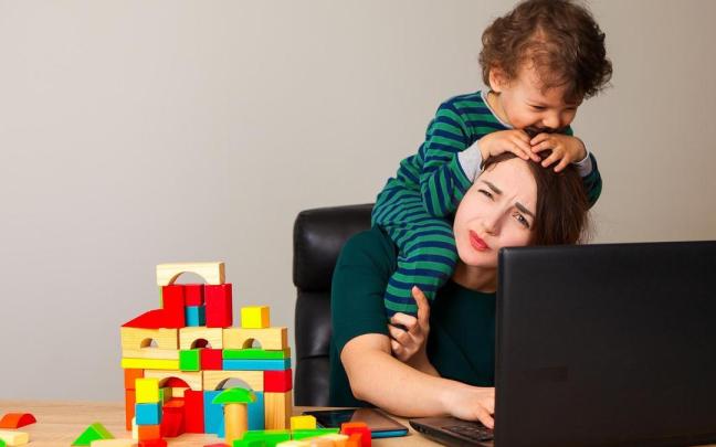 Una mujer intenta trabajar con su hijo subido a hombros. Una mujer intenta trabajar con su hijo subido a hombros.