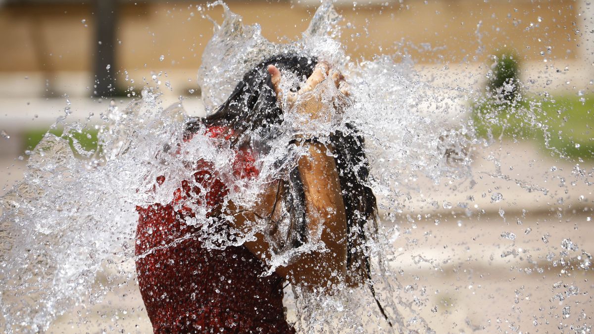 Una niña se refresca en una fuente durante la ola de calor